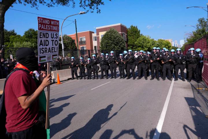 Police walk towards protesters who knock down a fence surrounding United Center at the Democrat ...