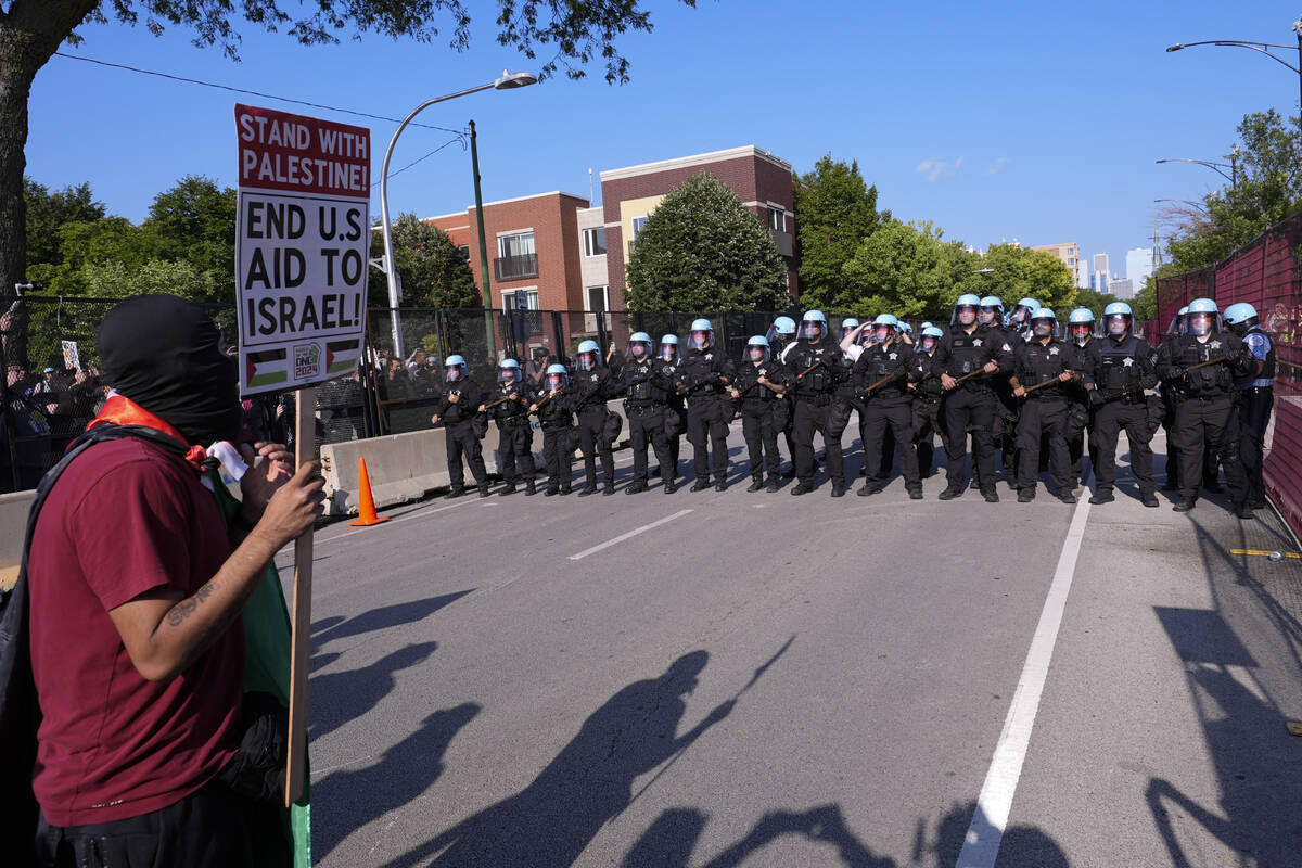 Police walk towards protesters who knock down a fence surrounding United Center at the Democrat ...