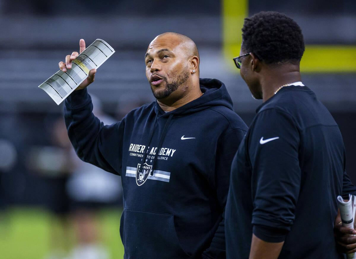 Raiders head coach Antonio Pierce talks with another coach during an open practice at Allegiant ...