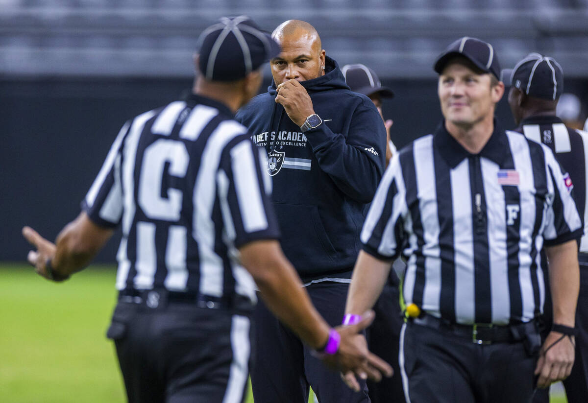 Raiders head coach Antonio Pierce talks looks on as officials joke around during an open practi ...