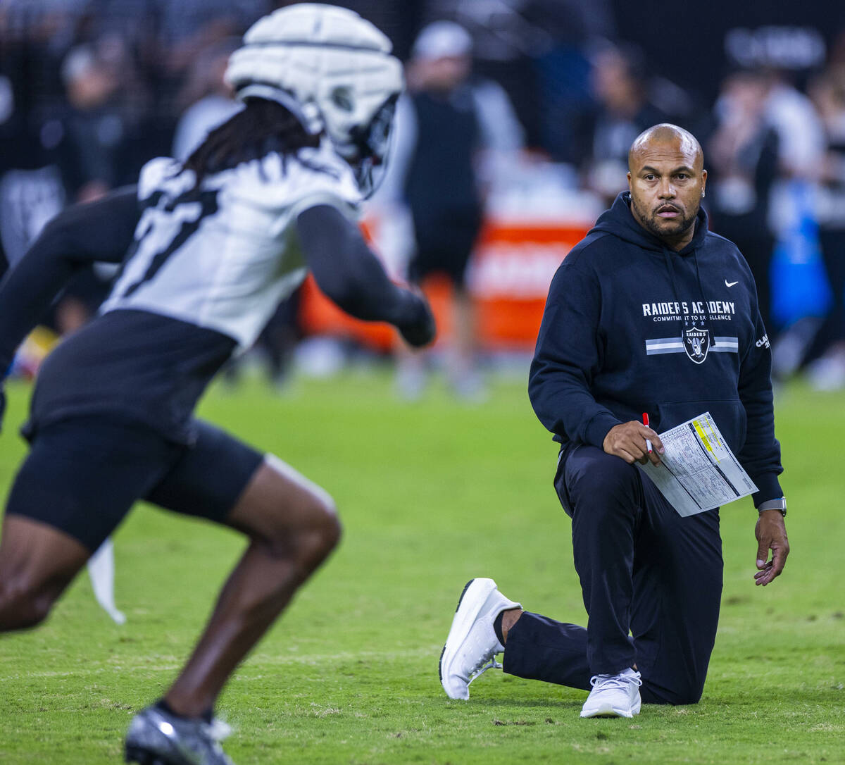 Raiders head coach Antonio Pierce watches wide receiver Davante Adams (17) during an open pract ...