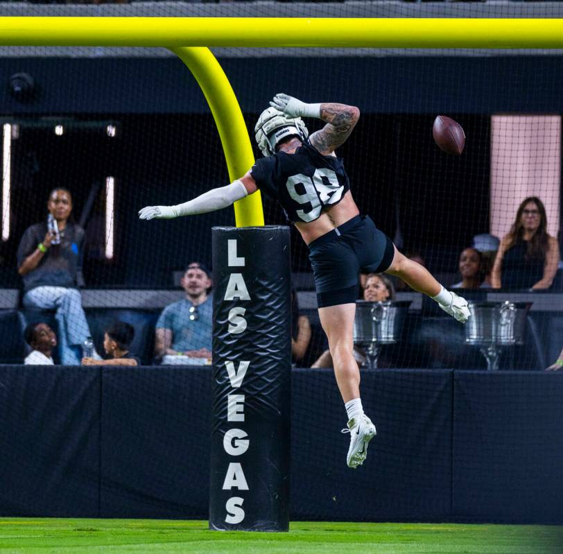 Raiders defensive end Maxx Crosby (98) dunks the ball over the crossbar on a score after an int ...