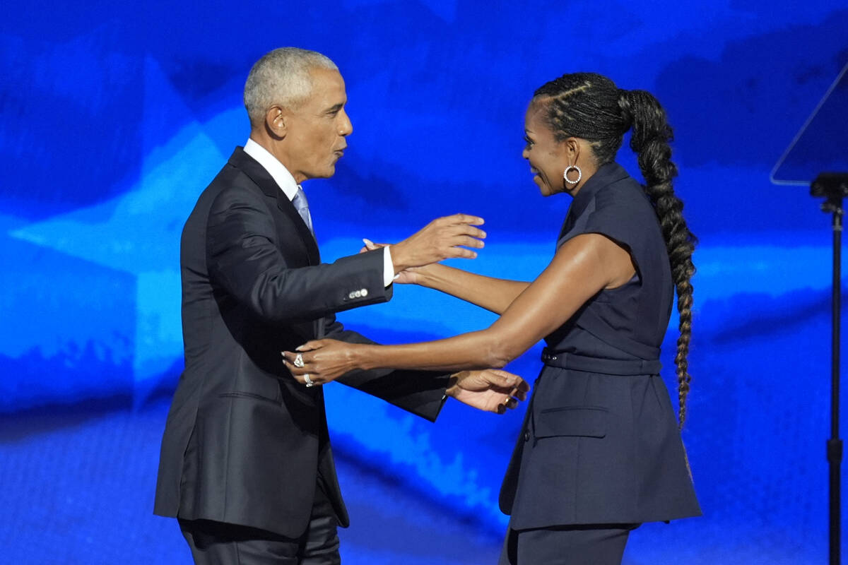 Former President Barack Obama, left, and former first lady Michelle Obama, right, embrace at th ...