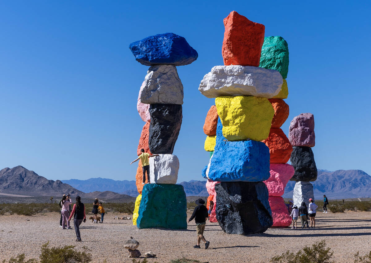 A visitor stands atop of one of the rocks as he and others stop by to see the Seven Magic Mount ...