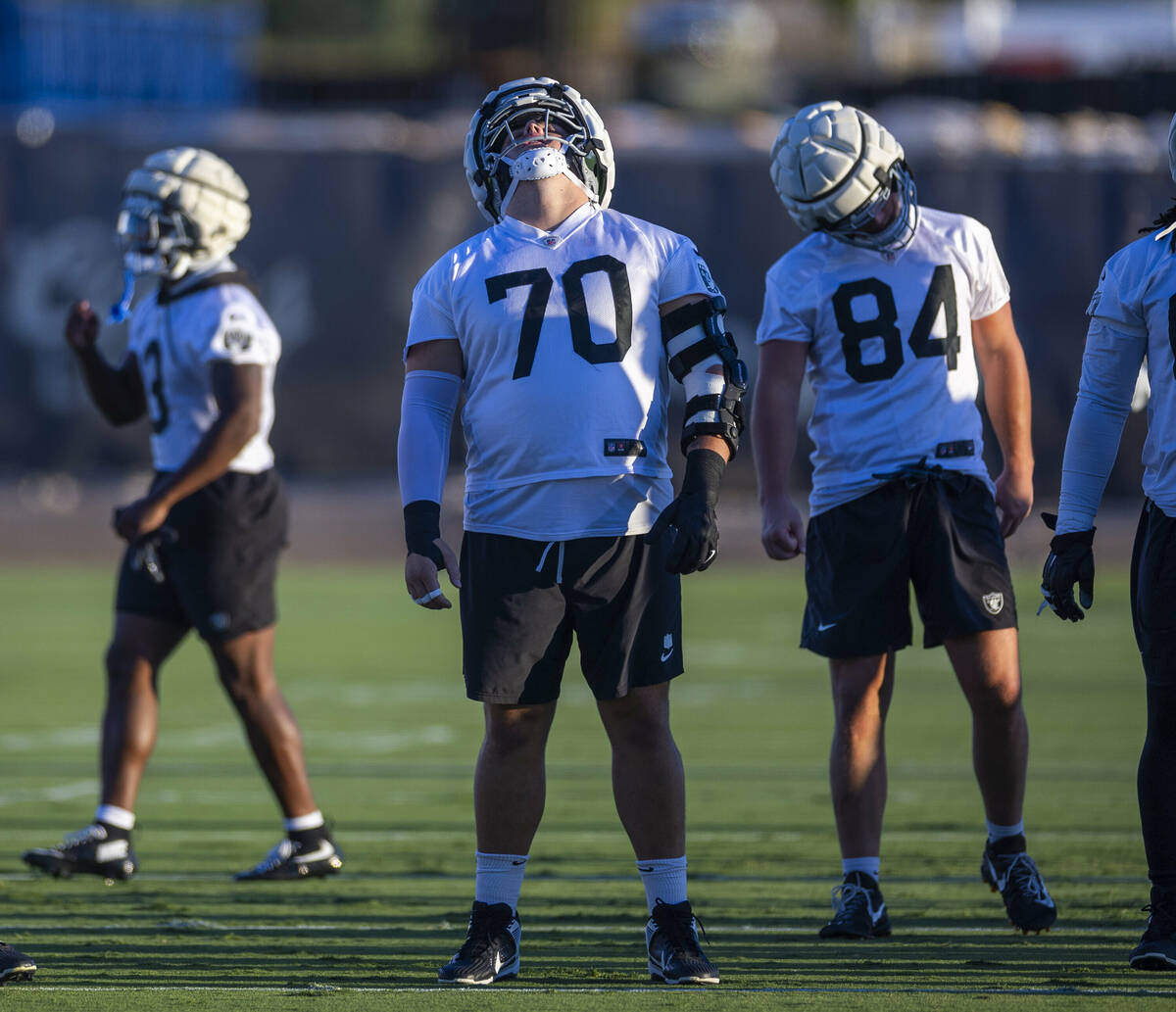 Raiders guard Jackson Powers-Johnson (70) and teammates do neck rolls while stretching during p ...