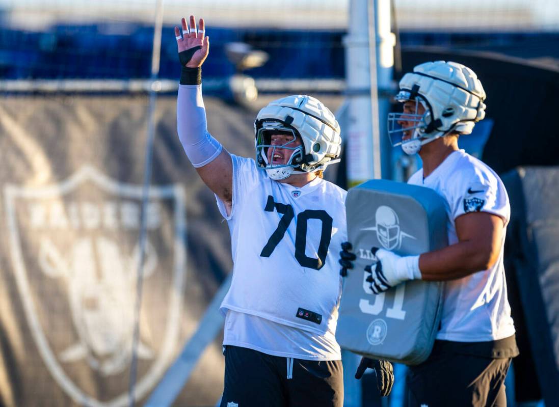 Raiders guard Jackson Powers-Johnson (70) signals to a coach beside guard Clark Barrington (64) ...