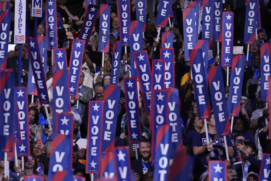 Delegates hold signs as former President Barack Obama speaks during the Democratic National Con ...