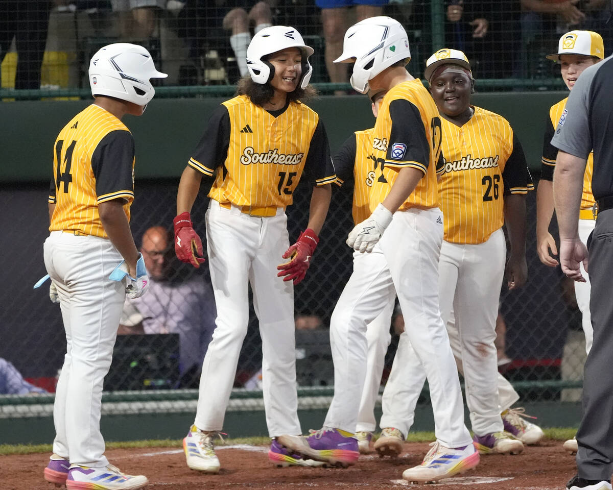 Lake Mary, Fla.'s Garrett Rohozen (22), third from front left, is greeted at home plate by team ...