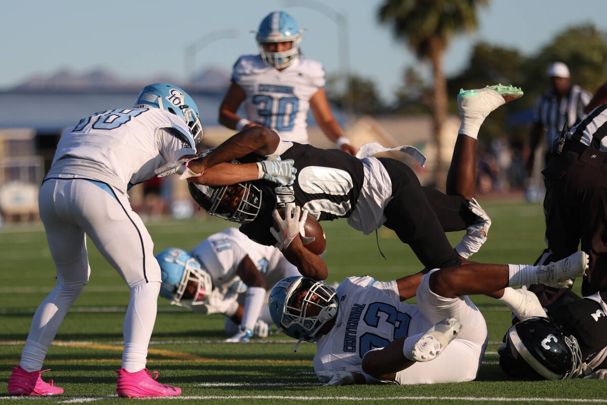 Desert Pines running back Marcus Williams (20) tumbles through defense by Centennial’s B ...