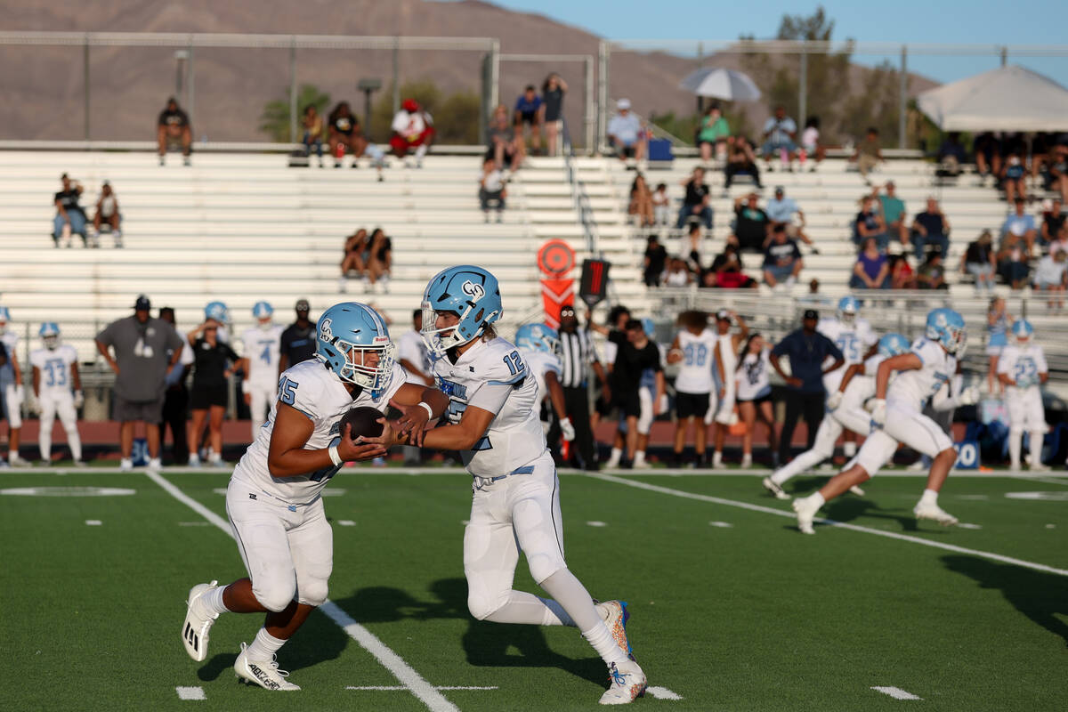 Centennial quarterback James Monaghan IV (12) hands the ball off to wide receiver Mason Garza ( ...