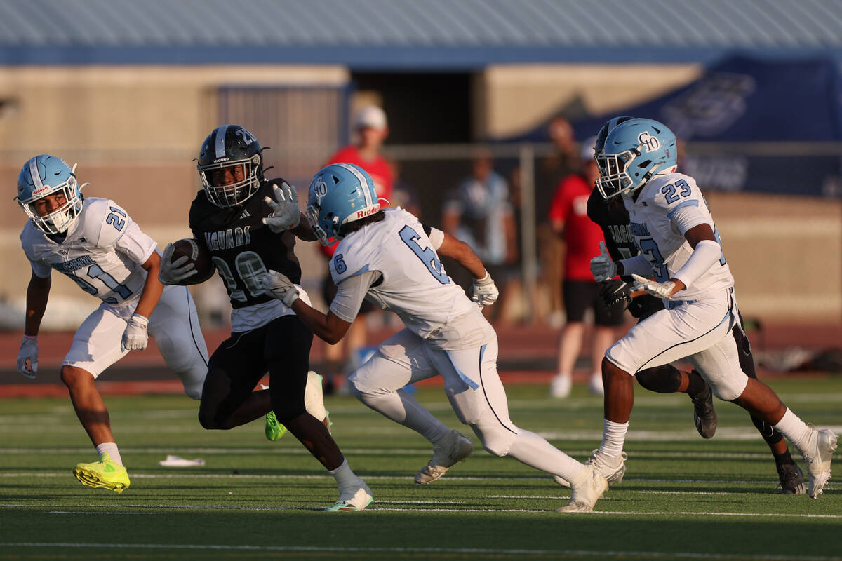 Desert Pines running back Marcus Williams (20) carries the ball up the field with pressure from ...