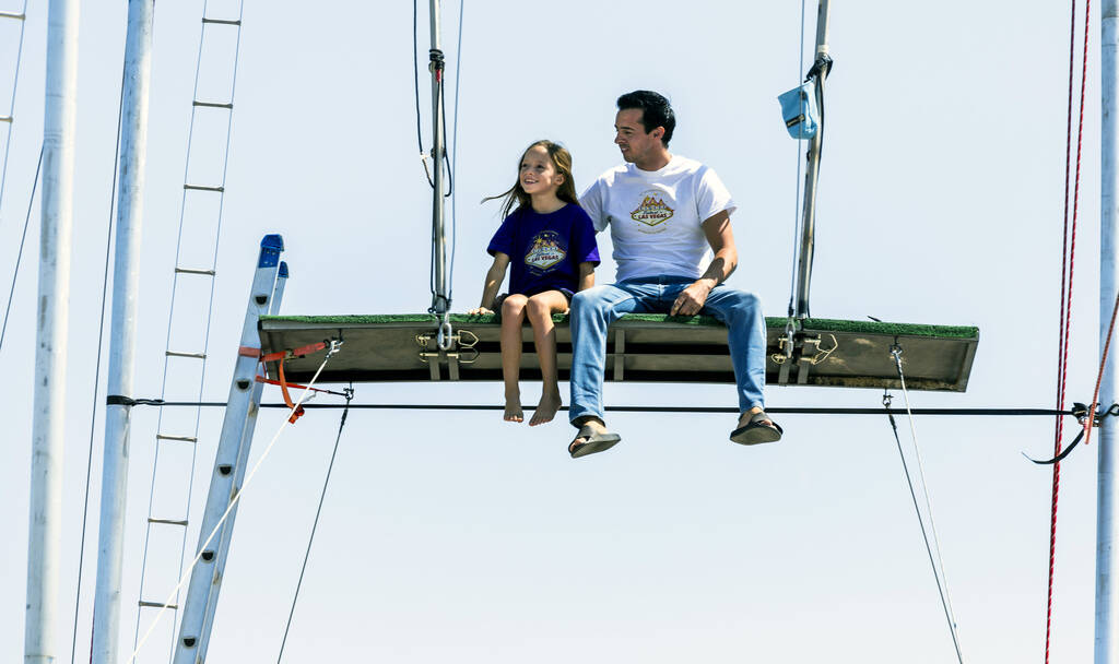 Renato Fernandes with his daughter Katalina sitting atop of a platform on their backyard trapez ...