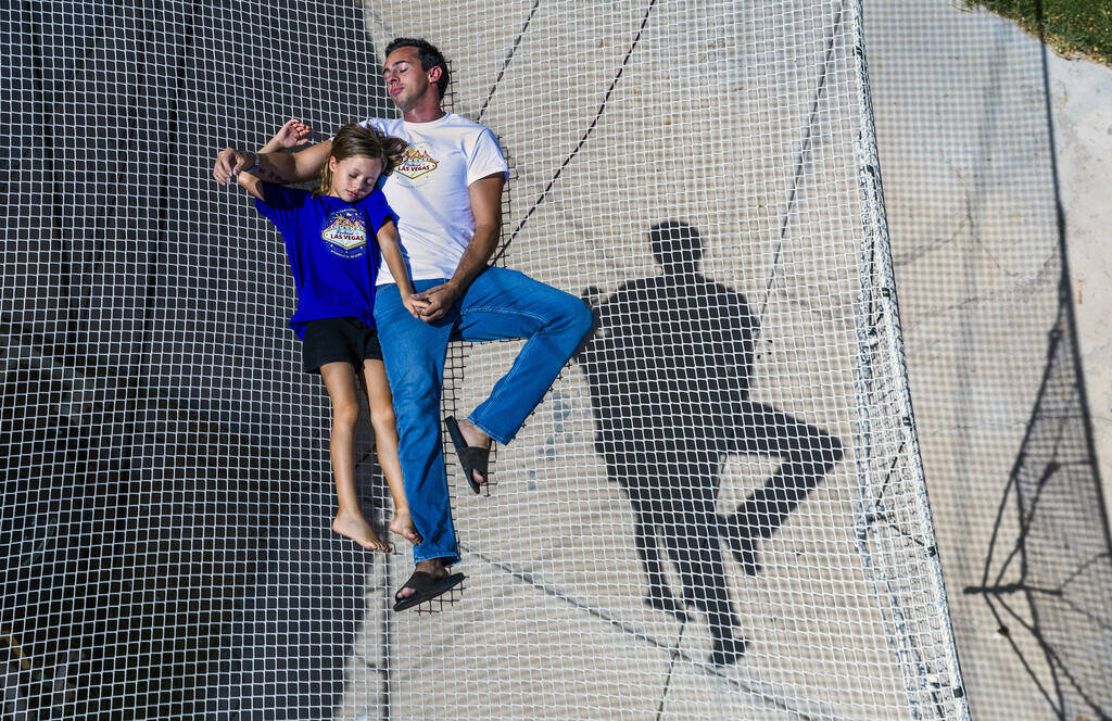 Renato Fernandes with his daughter Katalina relax atop of the netting on their backyard trapeze ...