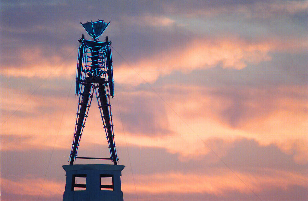 FILE - In this Aug. 26, 2002 file photo the sun rises behind a wood and neon statue, the center ...