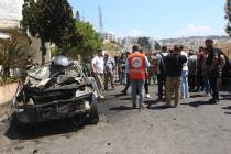 Lebanese security and emergency personnel gather around a burnt car that was reportedly targete ...