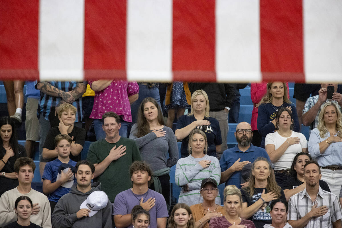 Spectators place their hands on their chests as the national anthem is sung before the volleyba ...