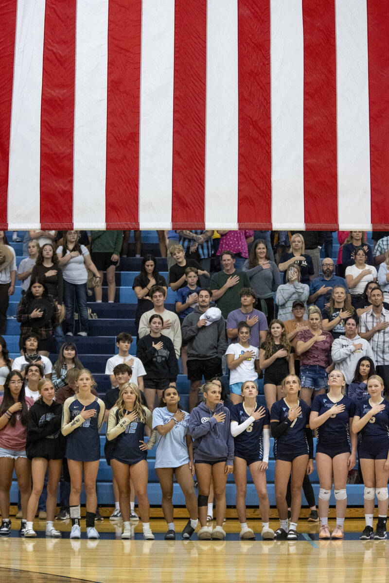 The Foothill volleyball team places their hands on their chests as the national anthem is sung ...