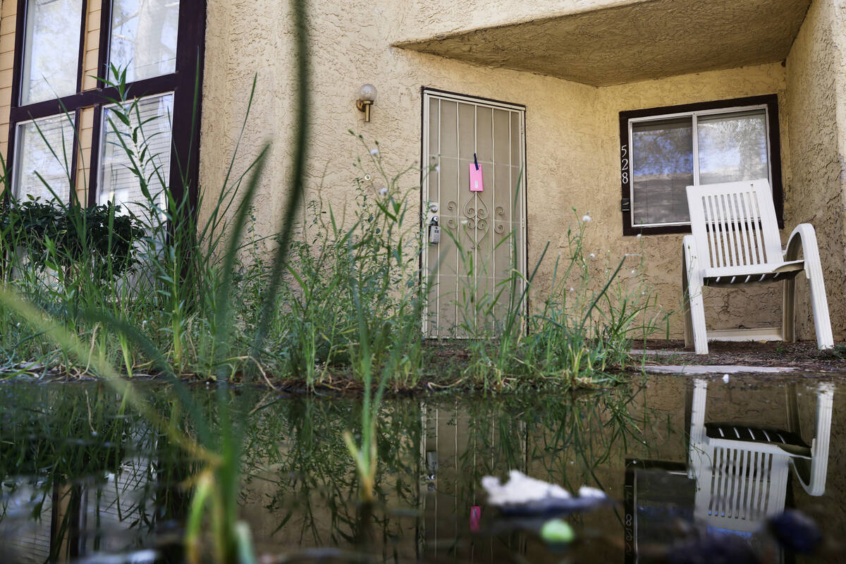 Water pools near a townhome with a notice from the city taped to a door in Somerset Park in Hen ...