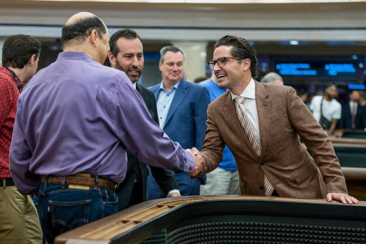 Gambler Juan Fresquez Jr., left, shakes hands with Caesars Regional Vice President Sean McBurne ...