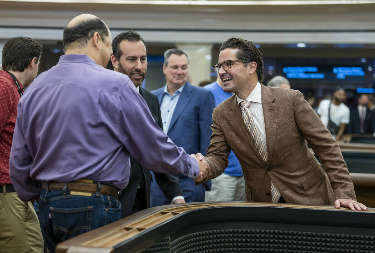 Gambler Juan Fresquez Jr., left, shakes hands with Caesars Regional Vice President Sean McBurne ...