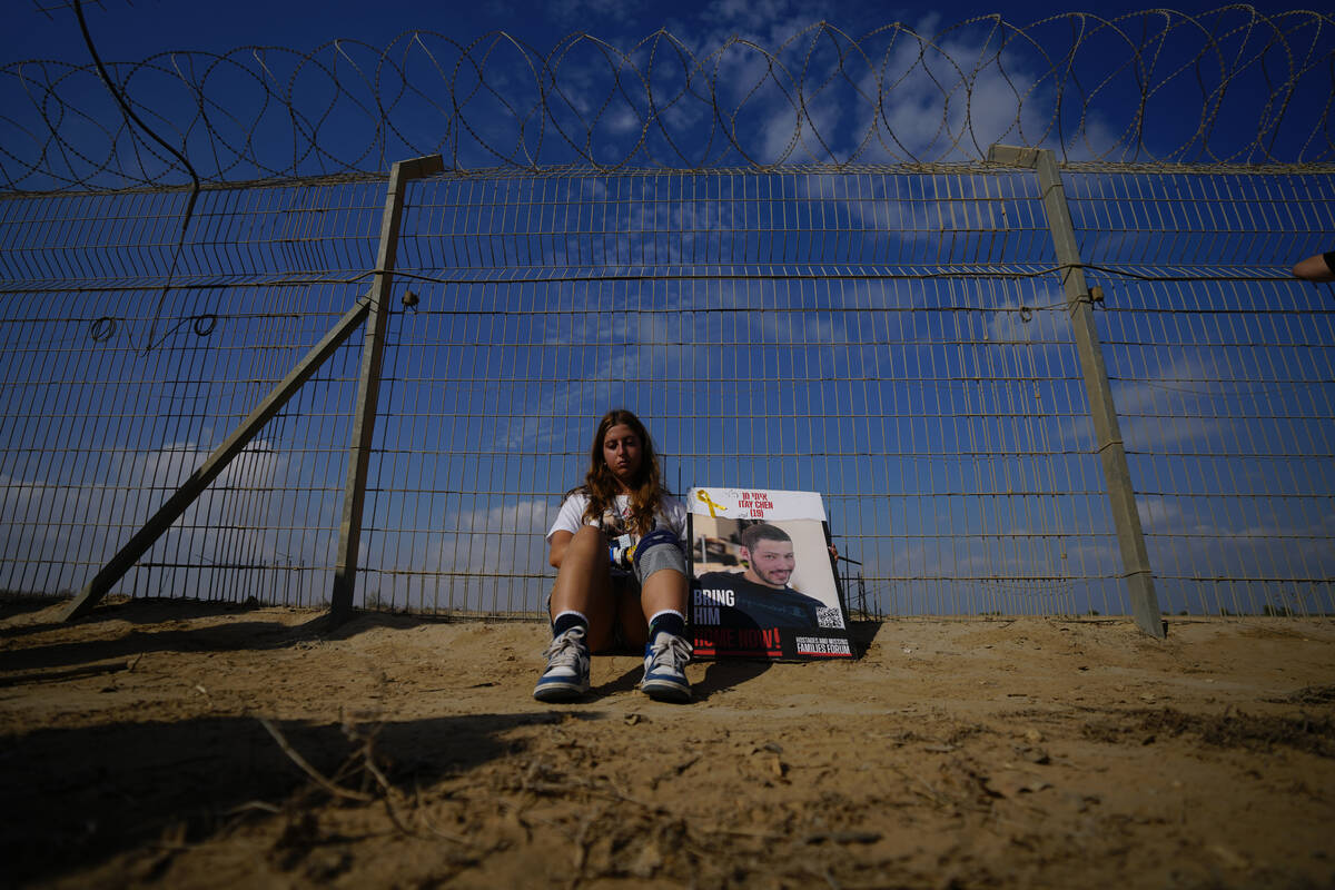 A woman sits next to a fence as relatives and friends of hostages held in the Gaza Strip by the ...