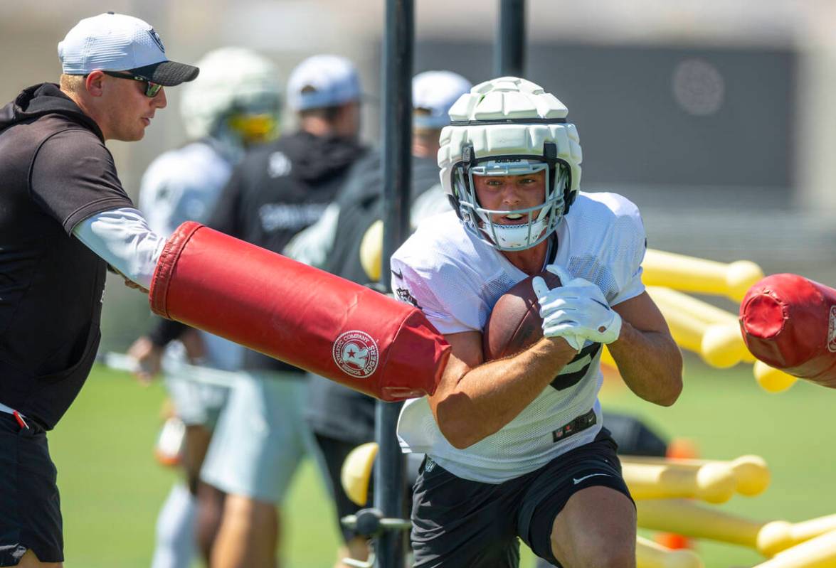 Raiders tight end Brock Bowers (89) takes a hit while running with the ball on a drill during p ...