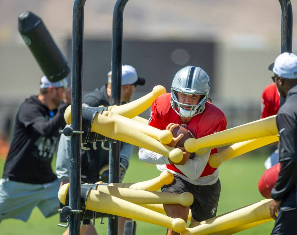 Raiders quarterback Gardner Minshew (15) blasts through plastic arms on a run during a drill in ...