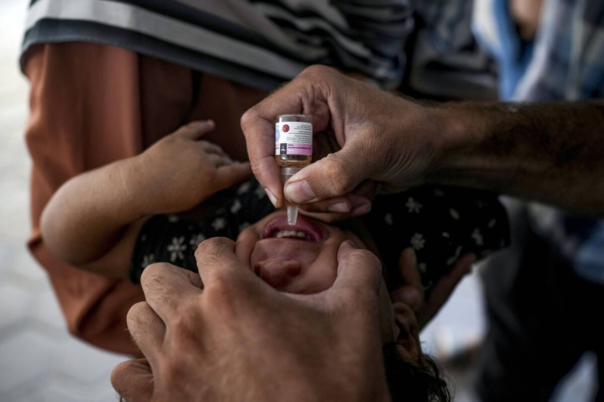 A health worker administers a polio vaccine to a child at a hospital in Deir al-Balah, central ...