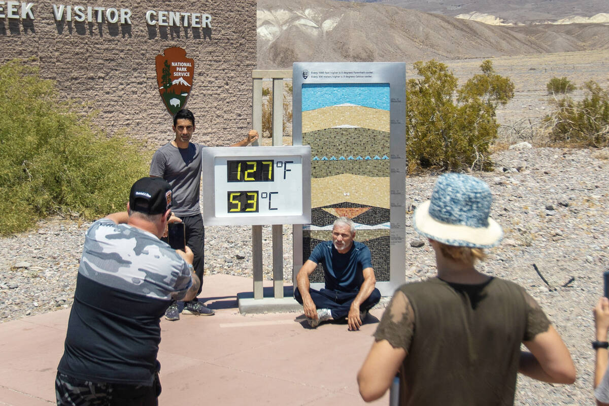 Tourists take photographs in front of the Furnace Creek Visitor Center thermometer on July 8, 2 ...