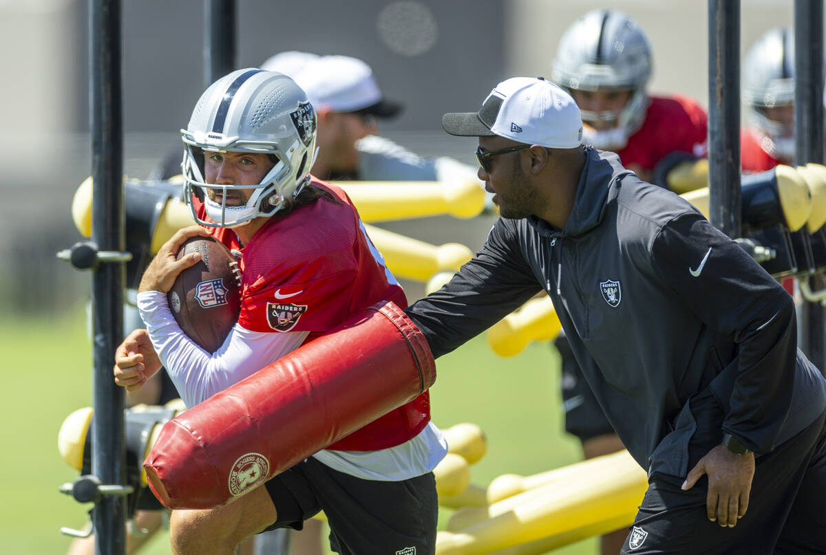 Raiders quarterback Gardner Minshew (15) fights off a swipe at the ball on a run during a drill ...