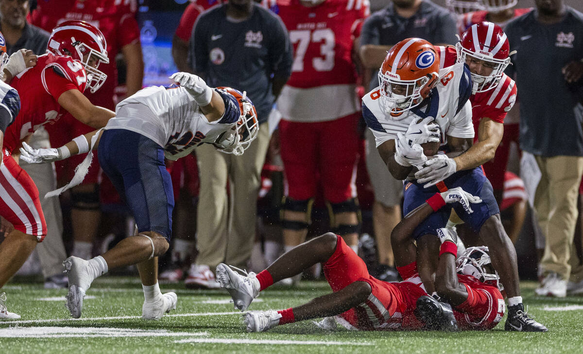 Bishop Gorman wide receiver Greg Toler (8) ensures to hold on to the ball while taken down by M ...