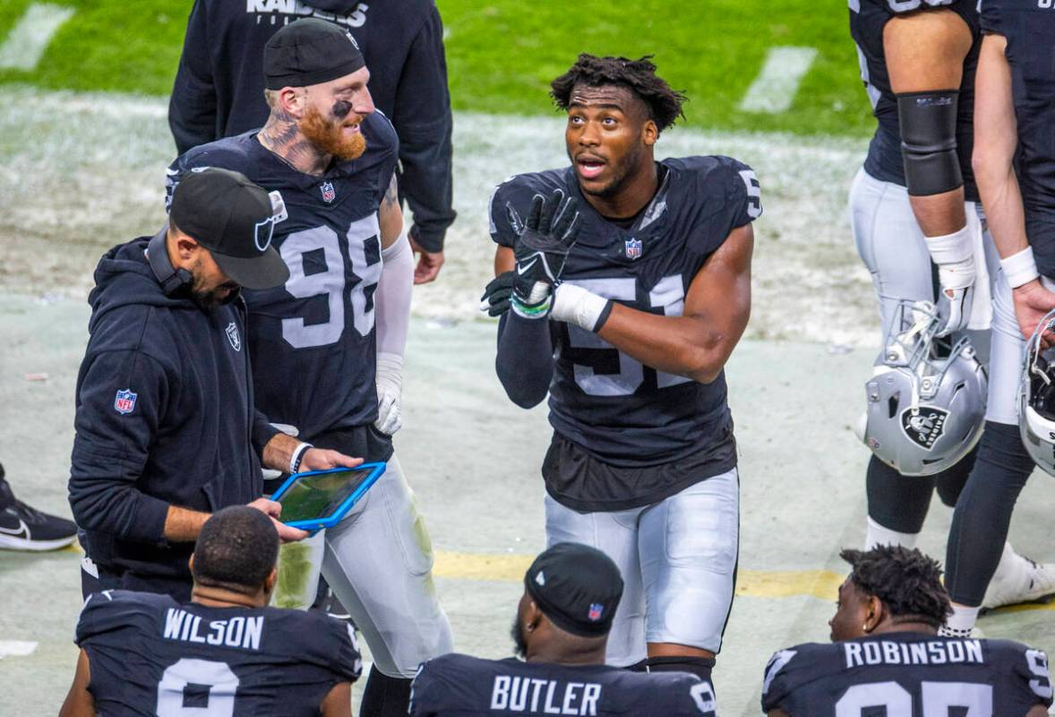 Raiders defensive end Malcolm Koonce (51) retells a play to defensive end Maxx Crosby (98) and ...