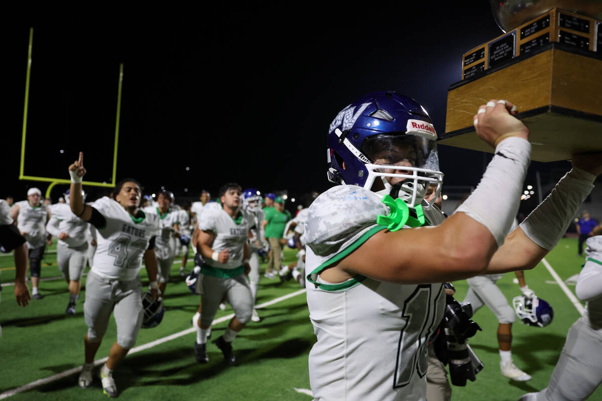 Green Valley’s Roman Adams (18) carries the annual Henderson Bowl trophy to the fans aft ...