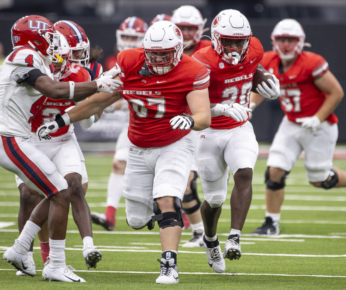 UNLV running back Kylin James (20) receives a block from offensive lineman Toby Moore (67) duri ...