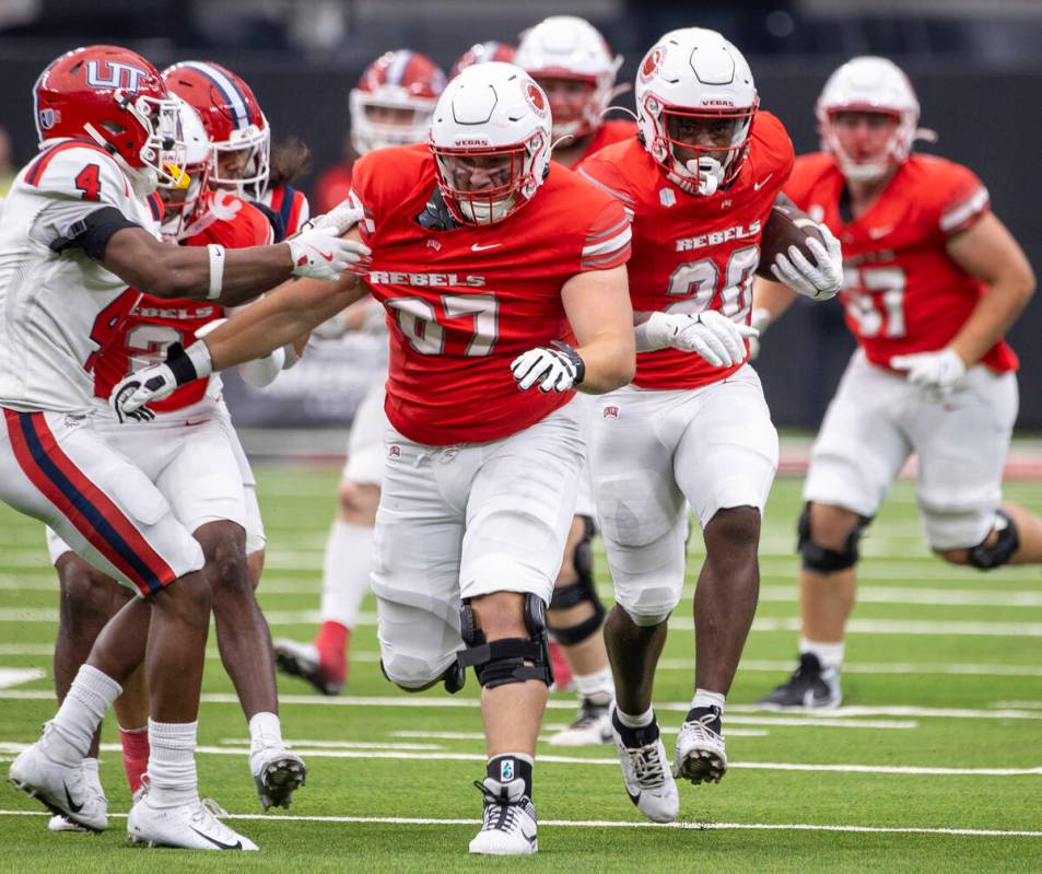 UNLV running back Kylin James (20) receives a block from offensive lineman Toby Moore (67) duri ...