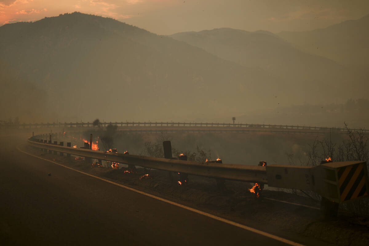 Wood posts along a railing on the side of a road smolders after the Line Fire swept through Sat ...