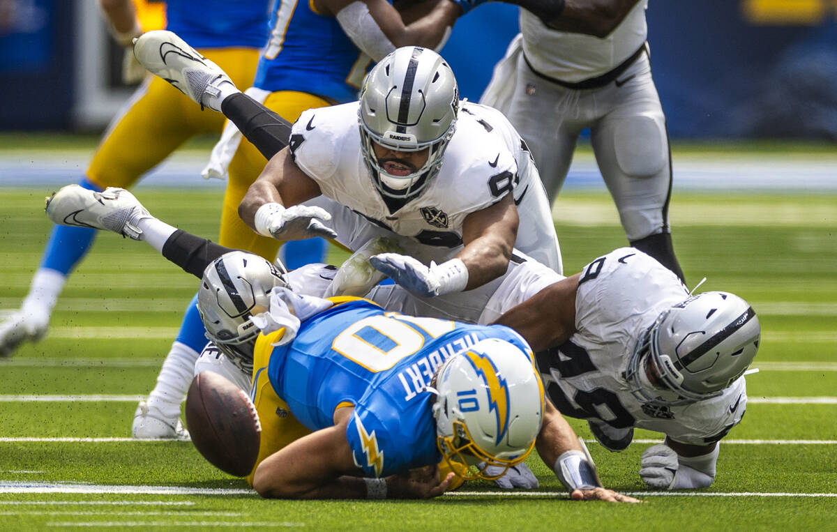 Los Angeles Chargers quarterback Justin Herbert (10) fumbles the ball after a big hit by Raider ...