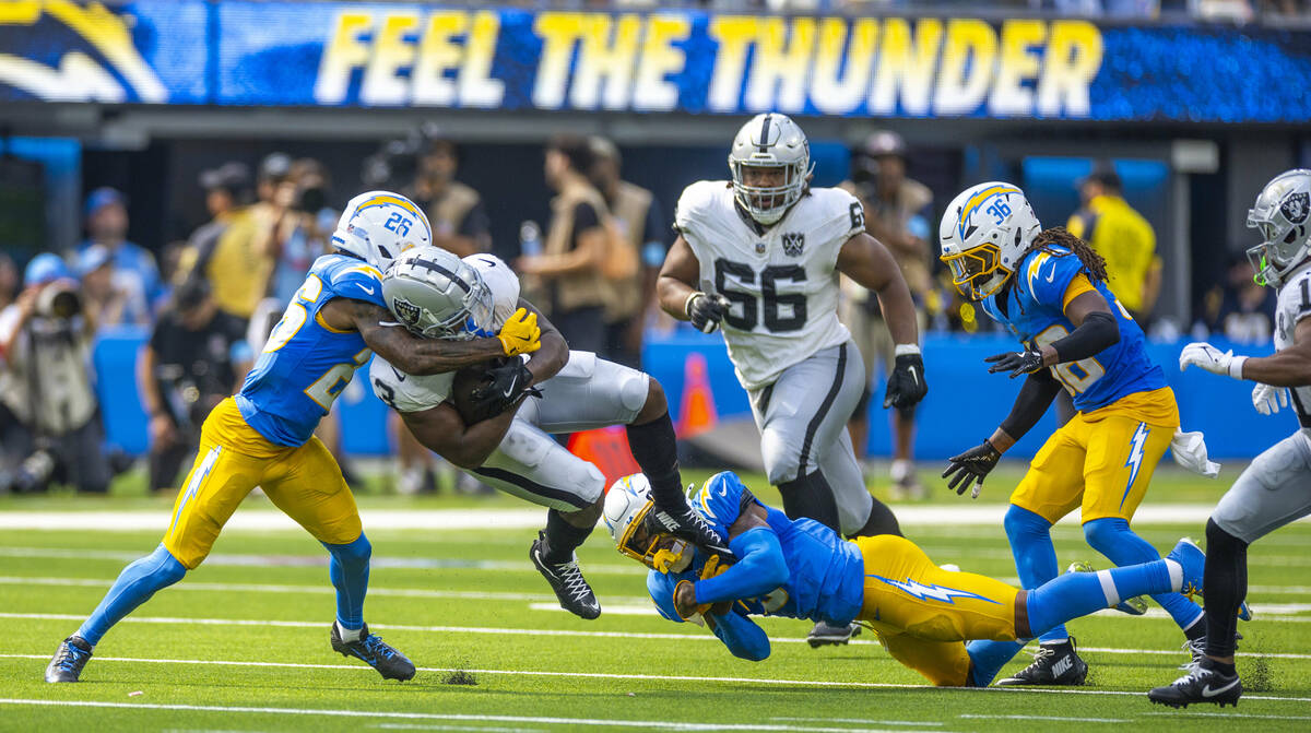 Raiders running back Zamir White (3) is team tackled by Los Angeles Chargers cornerback Asante ...