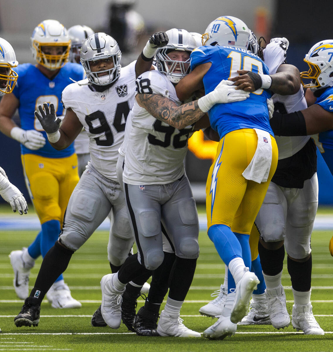 Raiders defensive end Maxx Crosby (98) wraps up Los Angeles Chargers quarterback Justin Herbert ...