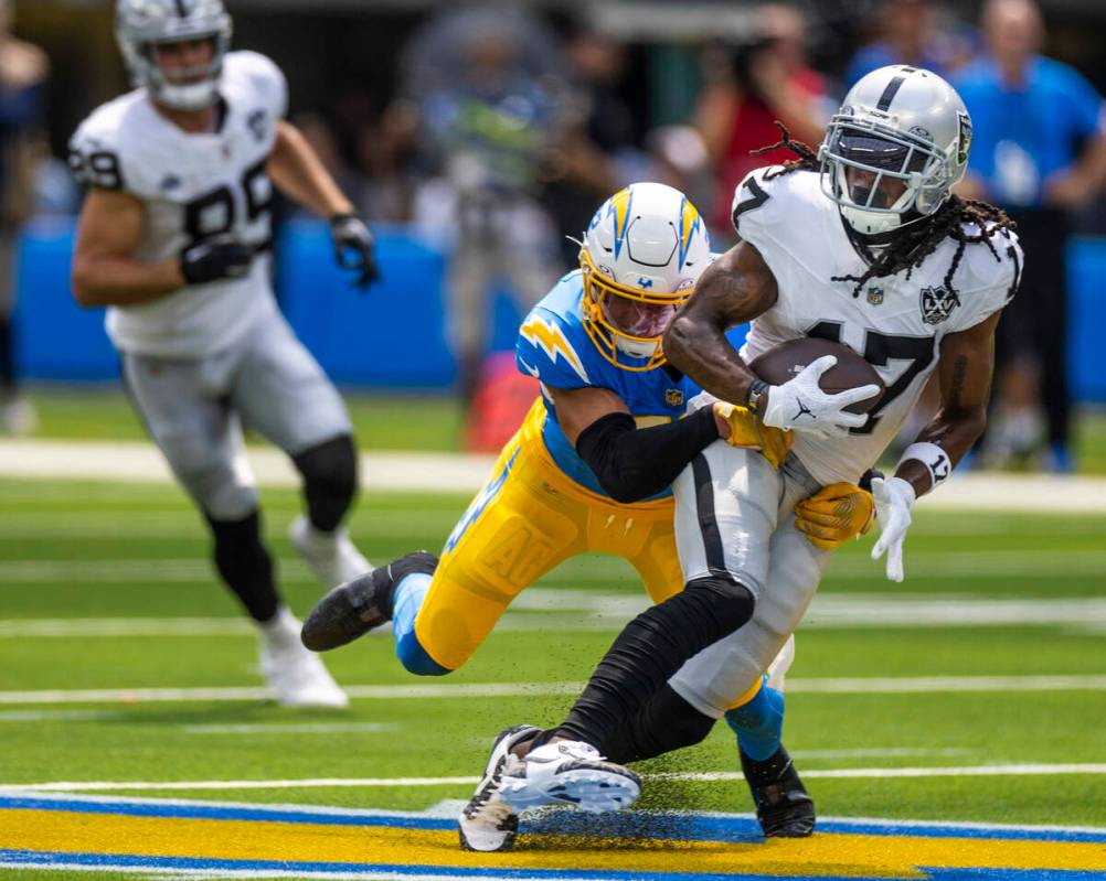 Raiders wide receiver Davante Adams (17) works to break a tackle attempt by Los Angeles Charger ...