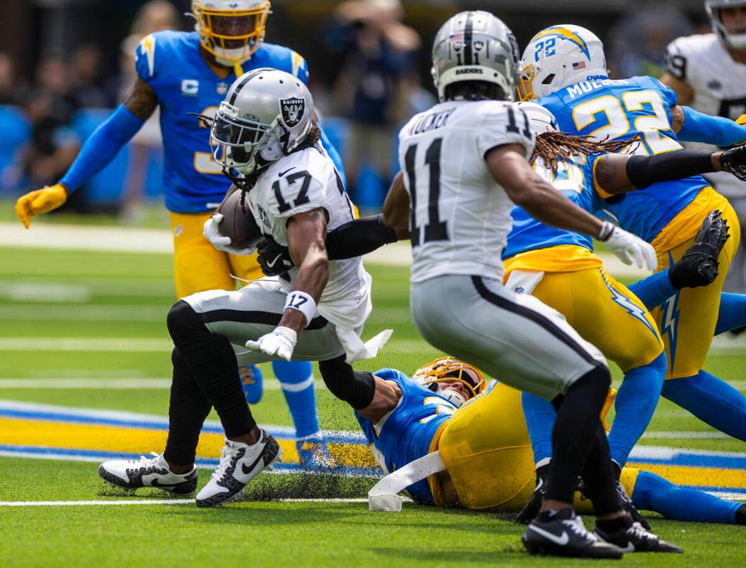 Raiders wide receiver Davante Adams (17) works to break a tackle attempt by Los Angeles Charger ...