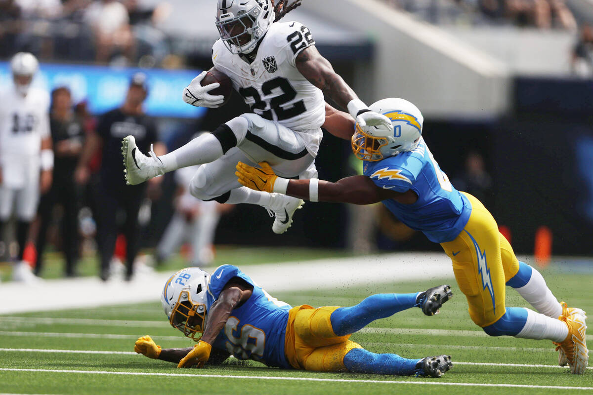 Raiders running back Alexander Mattison (22) hurdles over Los Angeles Chargers cornerback Asant ...