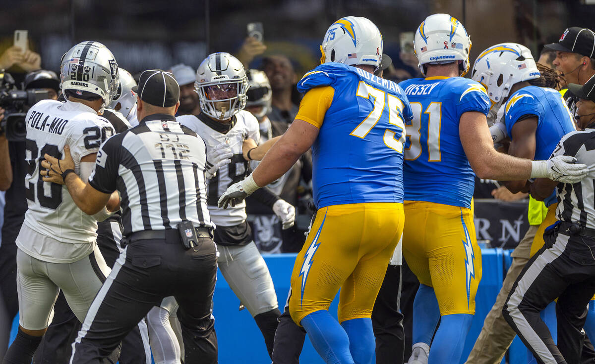 Raiders cornerback Jack Jones (18) is held back by Los Angeles Chargers center Bradley Bozeman ...