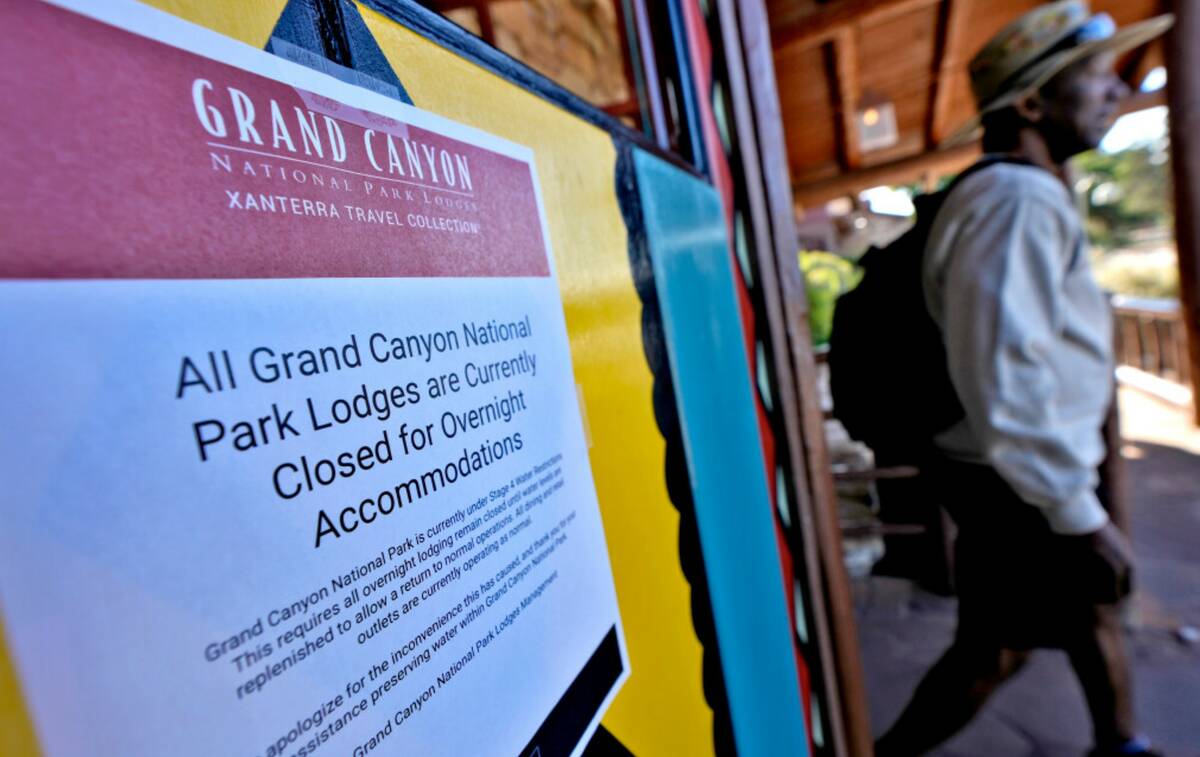 A sign denoting park lodge closures hangs on the door as a guest exits the Bright Angel Lodge, ...