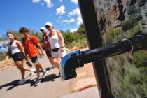 A group of day visitors walk past a closed water bottle tap along the Rim Trail on Thursday, Au ...