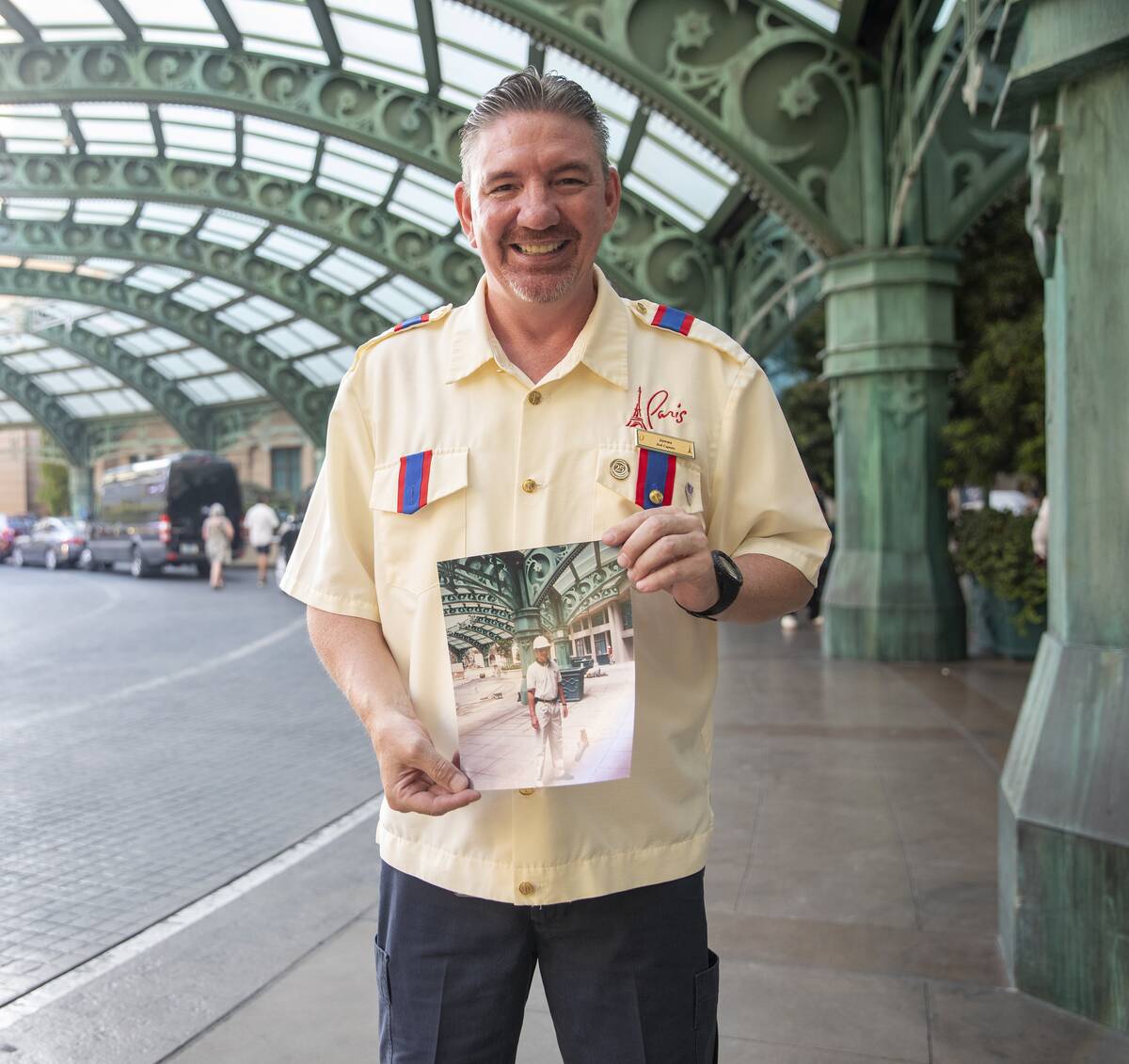 James Ealey, a Paris Las Vegas day-one employee, stands with a photograph from his first day of ...