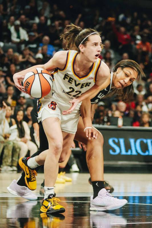 Aces center A'ja Wilson (22) peeks over at Indiana Fever guard Caitlin Clark (22) while guardin ...