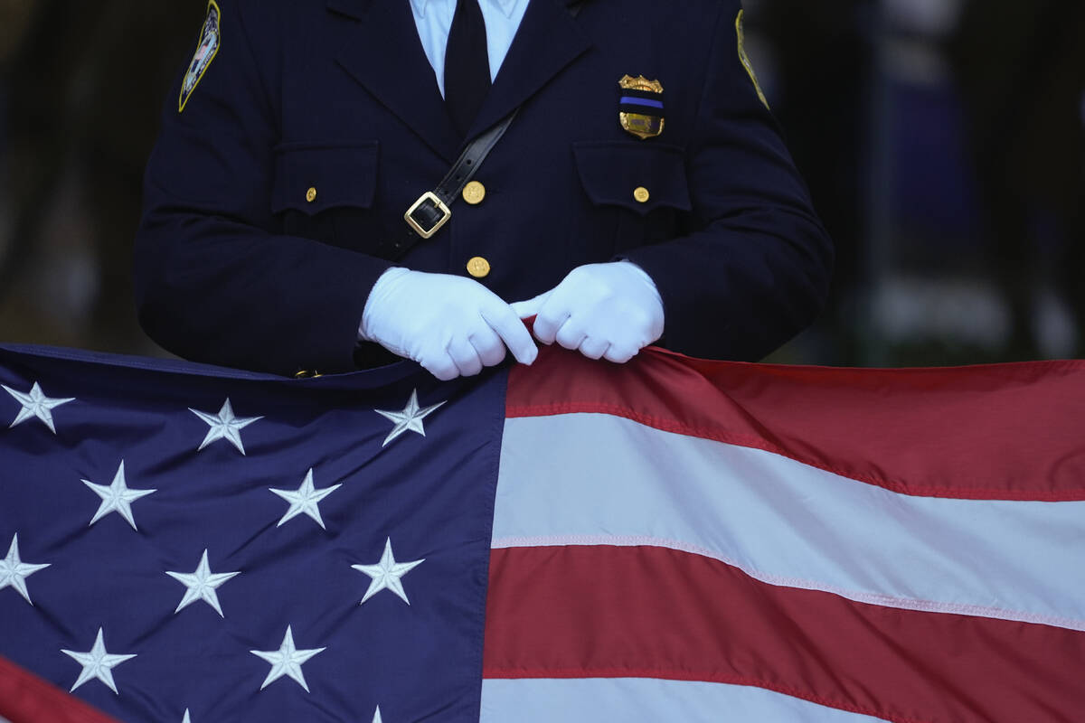 A New Jersey police officer holds an American Flag before the start of the ceremony at the 9/11 ...