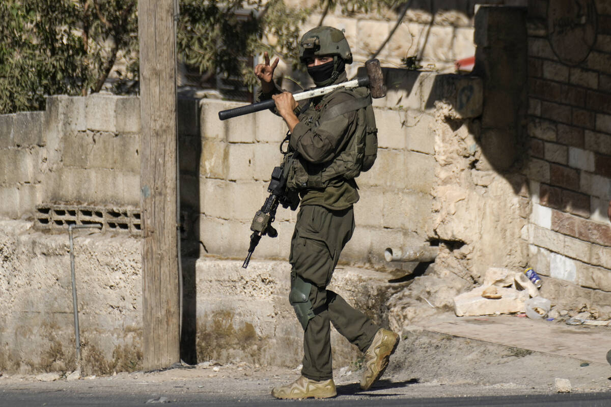 An Israeli soldier flashes a V-sign to photographers during an army raid in Tubas, West Bank, o ...