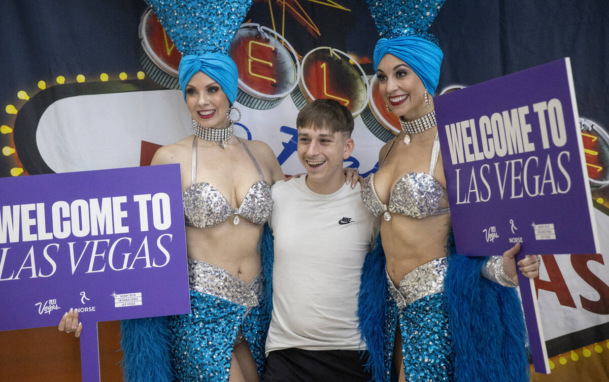 A young traveler poses for photographs with showgirls during the celebration of Norse Atlantic ...